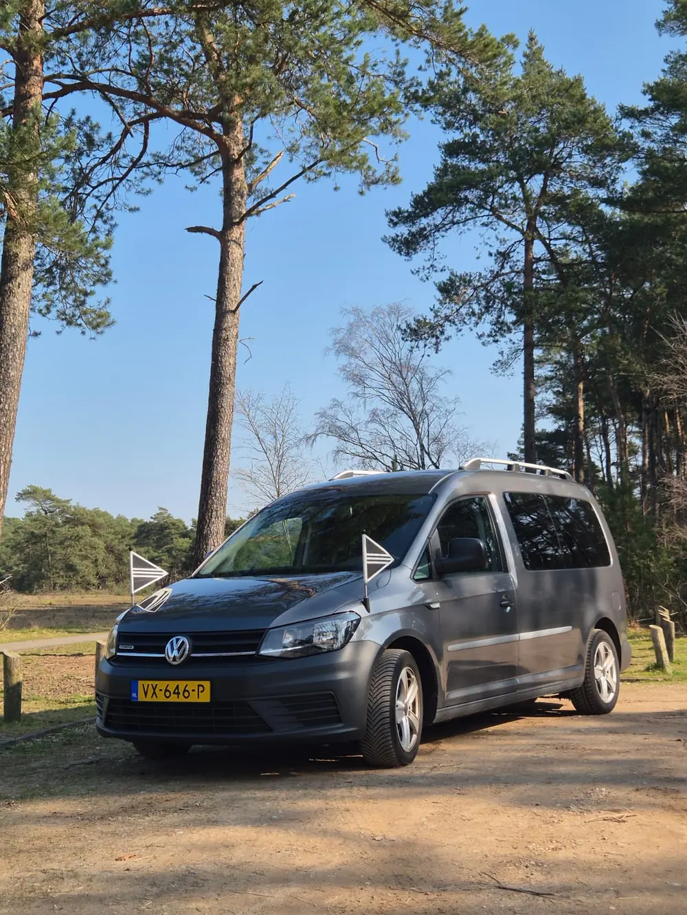 Bedrijfsauto van Raven en Verschoor met rouwvlaggen, op een bospad